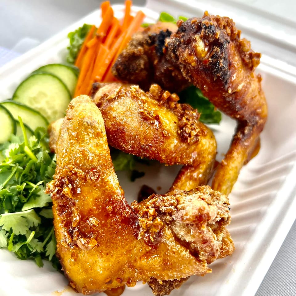 Fyre Wings' crispy, golden-brown wings with garlic bits, served with fresh cucumber, carrots, and cilantro.