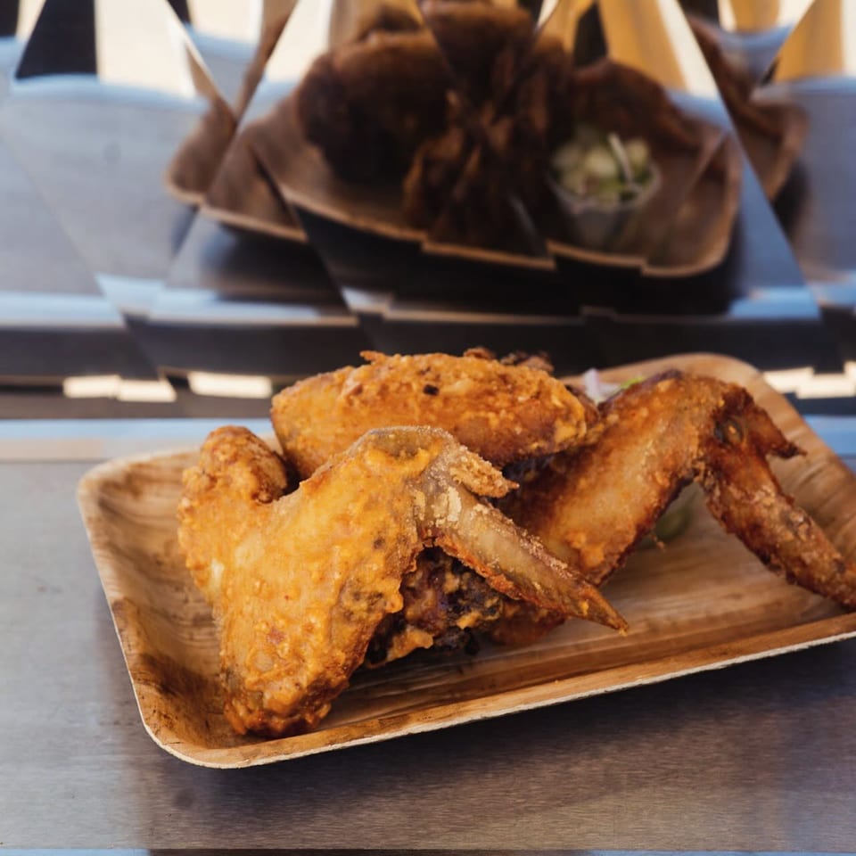 Crispy fried Fyre Wings on a wooden plate, with more wings blurred in the background.