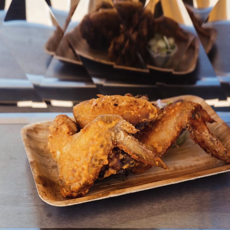 Crispy fried Fyre Wings on a wooden plate, with more wings blurred in the background.